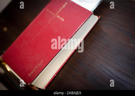 Santo chiuso rosso libro di preghiera in appoggio su di una tavola di chiesa. Foto Stock