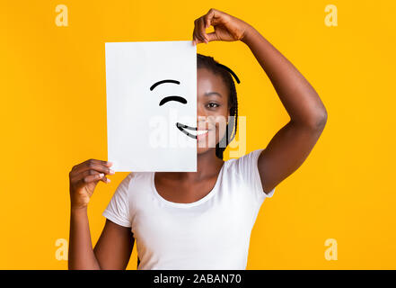 Nero donna che copre metà faccia con smiley immagine Foto Stock