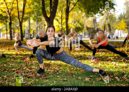 Un folto gruppo di sportivi stretching su erba verde in posizione di parcheggio Foto Stock