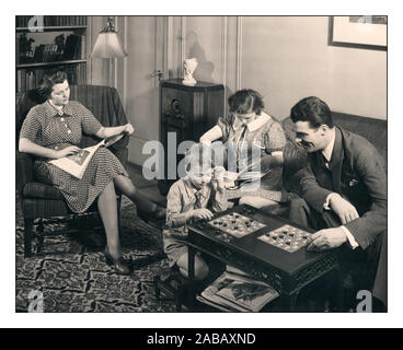 Famiglia di quattro persone vintage anni '1940 sedute insieme, a leggere e giocare a giochi da tavolo nel loro salotto insieme. 20 Century B&W Fotografia Post-War Home Life gruppo familiare di Home Economist 1946 Edizione di vivere insieme in famiglia Foto Stock