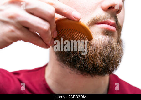 Giovane uomo ritratto con il suo pettine per barba e baffi bianchi su sfondo isolato Foto Stock