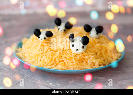 Nuovo anno 2020 - anno del ratto bianco. Insalata di carino - bianco mouse sul formaggio da uova e olive, bokeh di fondo Foto Stock