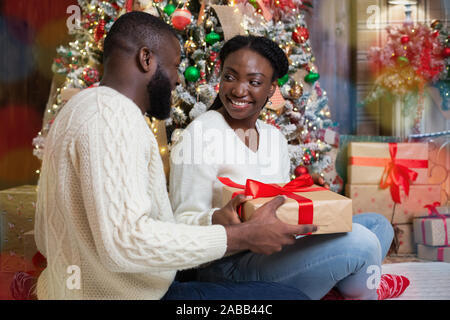 Nero amorevole marito sorprendente la sua moglie con il regalo di Natale  Foto stock - Alamy