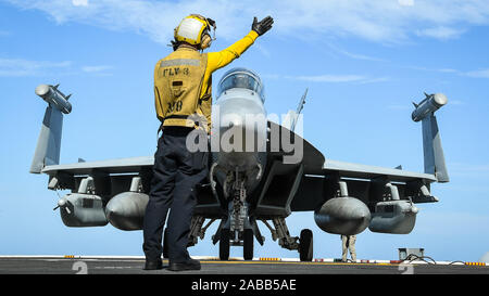 Stati Uniti Navy Aviation Nostromi Mate 3° di classe Derek Riley segnali per il pilota di una E/A-18G Growler elettronico jet da combattimento per decollare dal ponte di volo dell'Nimitz-class portaerei USS Theodore Roosevelt durante le operazioni Novembre 22, 2019 nell'Oceano Pacifico orientale. Foto Stock