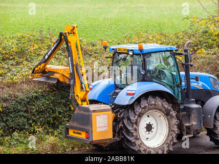 Azienda contraente agricoltore alla guida di un trattore taglio di siepi durante l'autunno con un McConnel tagliasiepi Foto Stock