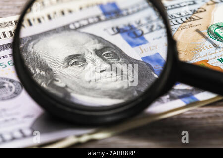 Verifica dei soldi per autenticità. Benjamin Franklin guarda attraverso una lente di ingrandimento nel telaio. Controllo di dollari Foto Stock