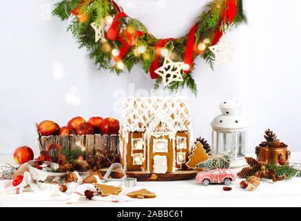 Gingerbread house sul tavolo di legno con una corona di fiori e decorazioni per le vacanze Foto Stock