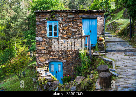 Vecchia casa di pietra con rustici in legno di colore blu di porte e finestre nel villaggio di Cerveira, Portogallo Foto Stock