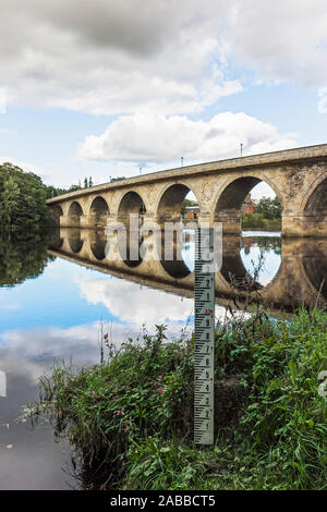 Acqua/livello di inondazione marcatore sul fiume Tyne a Hexham con Hexham road ponte che attraversa il fiume in Northumberland, Regno Unito. Foto Stock
