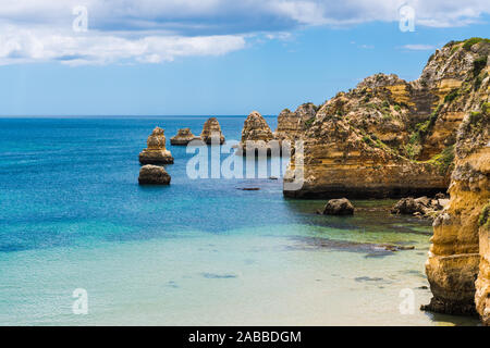 Seascape di calme acque blu e alte scogliere e formazioni rocciose a Praia da Dona Ana beach a Lagos sulla costa di Algarve in Portogallo Foto Stock