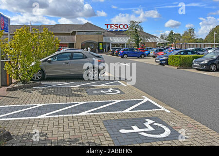 Parcheggio Disabili bay spazi al supermercato Tesco cliente parco auto icone verniciati sul blocco di pavimentazione città di Ely Cambridgeshire East Anglia England Regno Unito Foto Stock