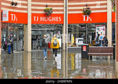 Wet Weather street scene & marciapiede riflessioni pioggia caduta su gli amanti dello shopping a piedi TJ Hughes negozio retail business nella Contea di Durham Durham Regno Unito Inghilterra Foto Stock