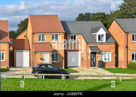 Auto parcheggiate esterno moderno nuova casa di sviluppo design assortiti con garage sulla scatola tenuta di Chilton vicino a Ferryhill nella Contea di Durham Regno Unito Inghilterra Foto Stock