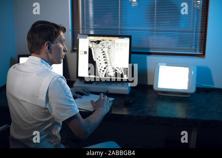 Nel laboratorio medico radiologo nella sala di controllo monitora lo scheletro e nervature del paziente MRI o CT Foto Stock