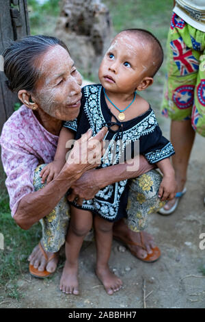 Nonna e nipote con facce in polvere (sunscreen) accolgono i visitatori nel villaggio di catena lungo il fiume Chindwin nel nord-ovest del Myanmar (Birmania) Foto Stock