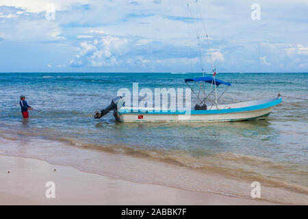Il capitano di un open barca che fissano la sua nave su una sabbiosa spiaggia messicana Foto Stock