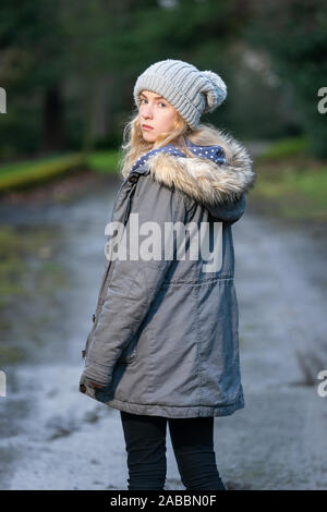 Bella femmina adolescente su un paese remoto percorso guardando indietro sulla spalla Foto Stock