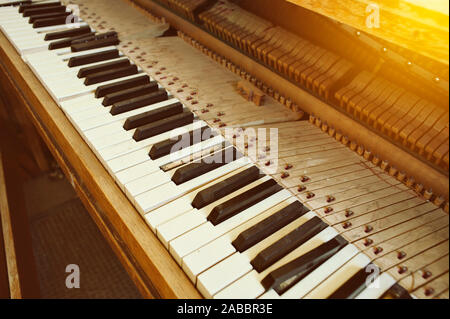 Angolo di visualizzazione del vecchio pianoforte con tasti rotti e polvere in illuminazione calda Foto Stock