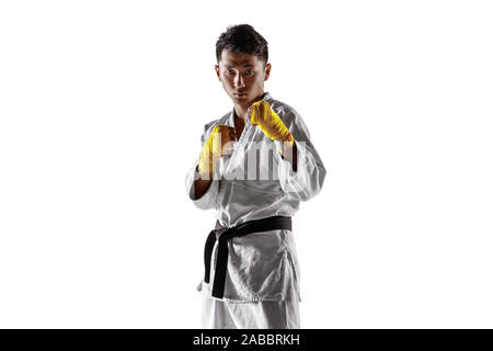 Fiducioso uomo coreano in kimono la pratica di combattimento a mani nude, arti marziali. Giovane maschio fighter con Allenamento cinture nere isolato su bianco di sfondo per studio. Concetto di stile di vita sano, sport. Foto Stock