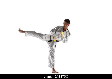 Fiducioso uomo coreano in kimono la pratica di combattimento a mani nude, arti marziali. Giovane maschio fighter con Allenamento cinture nere isolato su bianco di sfondo per studio. Concetto di stile di vita sano, sport. Foto Stock