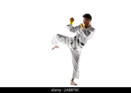 Fiducioso uomo coreano in kimono la pratica di combattimento a mani nude, arti marziali. Giovane maschio fighter con Allenamento cinture nere isolato su bianco di sfondo per studio. Concetto di stile di vita sano, sport. Foto Stock