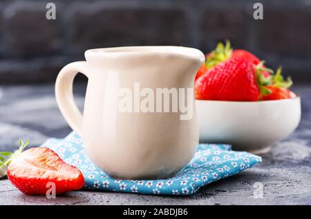 Il latte nel bricco e fragola su un tavolo Foto Stock