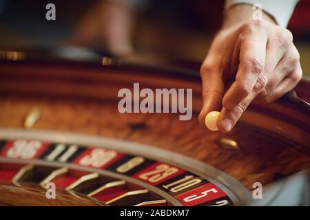 Mano di un croupier su una roulette whell in un casinò. Foto Stock