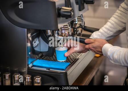 Barista con macchina per il caffè mentre il caffè per il cliente Foto Stock