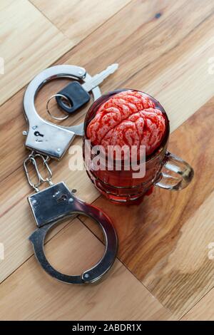 Cervello umano nel boccale di birra macerazione con le chiavi dell'auto e manette per alcolismo tossicodipendenze concept Foto Stock