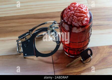 Cervello umano nel boccale di birra macerazione con le chiavi dell'auto e manette per alcolismo tossicodipendenze concept Foto Stock