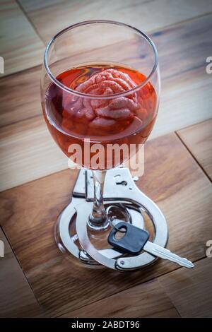 Cervello umano nel vino rosso di imbibizione di vetro con le chiavi dell'auto e manette per alcolismo tossicodipendenze concept Foto Stock