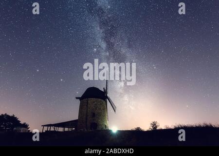 La Via Lattea di notte con un vecchio mulino a vento dentro il primo piano Foto Stock