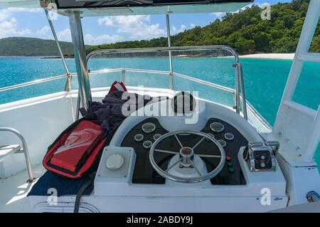 Captains bridge, tuga con il volante e i controlli sul pannello e spiaggia tropicale e turchese ble mare sullo sfondo Foto Stock