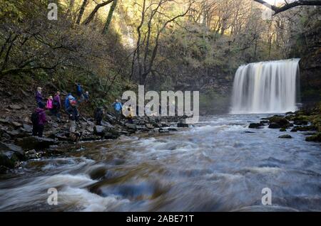 Persone turisti guardando Sgwd yr Eira sulla cascata Afon Mellte Fiume Ystradfellte Pontneddfechan Parco Nazionale di Brecon Beacons Fforest Fawr Geopark Foto Stock