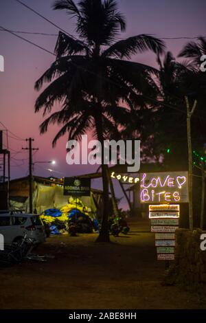 Una scritta al neon che conduce ad un bar tropicale in Goa, India, al tramonto. Foto Stock