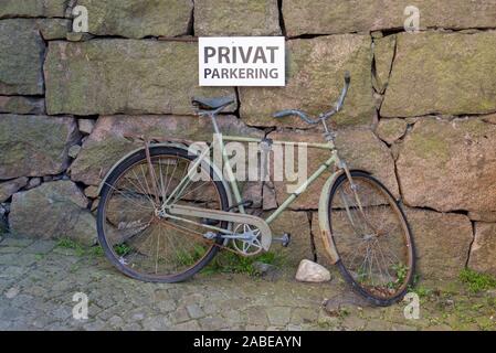 09 luglio 2019, Svezia, Fjällbacka: vista di una bicicletta arrugginita. Vi è un cartello con la scritta "Privatparkplatz' al di sopra di esso. Foto: Stephan Schulz/dpa-Zentralbild/ZB Foto Stock