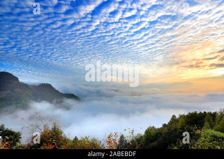 Pesce-scala-come cloud, noto anche come Altocumulus translucidus, che indica una grave aria fredda, appeso sopra la montagna di giallo, formando un meraviglioso na Foto Stock