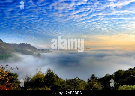 Pesce-scala-come cloud, noto anche come Altocumulus translucidus, che indica una grave aria fredda, appeso sopra la montagna di giallo, formando un meraviglioso na Foto Stock