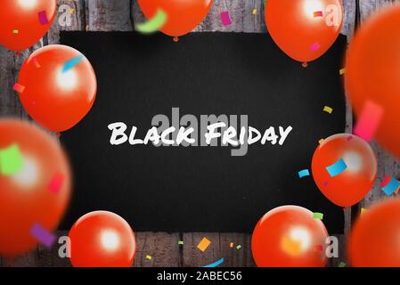 Blak venerdì vendita concetto con il testo su carta nera circondato con red ballons e coriandoli. Foto Stock