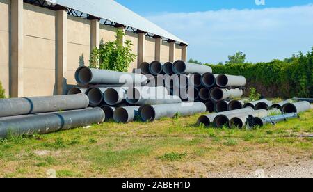 Pile di blu in PVC tubi di acqua in pila su open storage a un factory Foto Stock