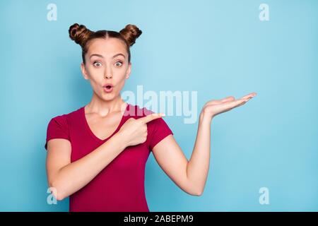 Foto di crazy eccitato allegro stupore ragazza tenendo lo spazio vuoto sul suo lato rivolto verso di esso con indice in t-shirt rossa labbra pouted isolato Foto Stock