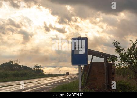 Il "Bus stop' e di orientamento per la superstrada in umido con appena scesa acqua piovana. Sullo sfondo la silhouette di un camion che attraversano la superstrada. Foto Stock