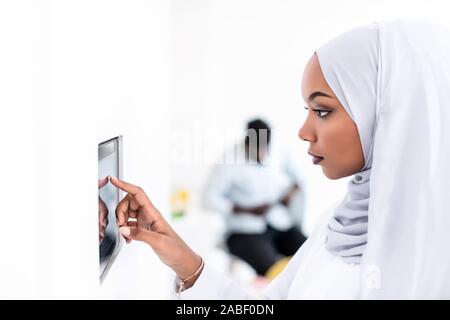 Giovane africana moderna donna musulmana utilizzando smart nella schermata iniziale del sistema di controllo Foto Stock
