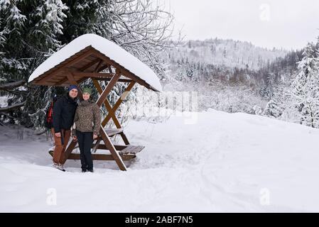 Contenuto giovane in piedi sotto un riparo durante le escursioni in inverno Foto Stock