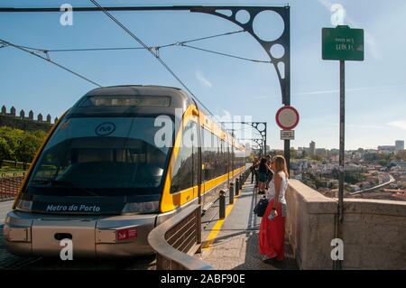 Moderno tram elettrico parte della rete dei trasporti pubblici a Porto, Portogallo attraversa il fiume Douro sulla sommità del Dom Luis i bridge un doppio-d Foto Stock