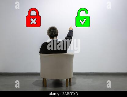 Un uomo guarda a due lucchetti e punti a quella aperta. Concetto di scelta, nuove soluzioni. Sicurezza elettronica login Foto Stock
