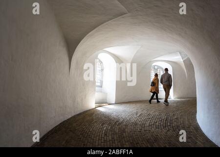 Giovani coppie che camminano, vista posteriore dei giovani che salgono la scala equestre o la rampa elicoidale all'interno del Rundetaarn, centro di Copenaghen, Danimarca. Foto Stock