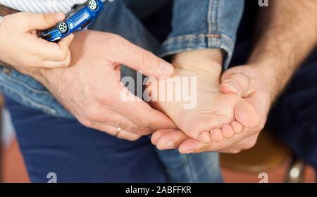Il pediatra esamina il bambino i piedi, il dermatologo considera i talloni, piede e tallone massaggio.Concetto di esame e di trattamento dei bambini Foto Stock
