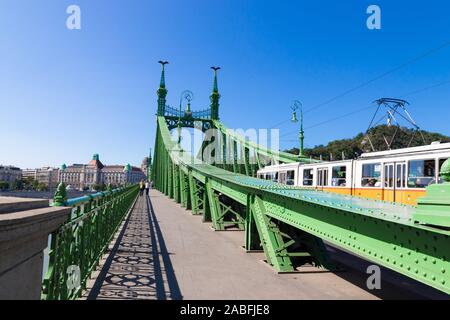 Budapest, Ungheria - 13 Settembre 2019: Bella di metallo verde ponte della libertà o della libertà Bridge e trenino giallo su un giorno di estate Foto Stock