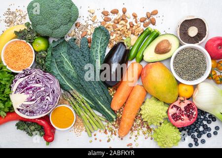 Vegane. Frutta Ortaggi lenticchie spezie erbe noci e semi su un bianco sullo sfondo di ardesia Foto Stock